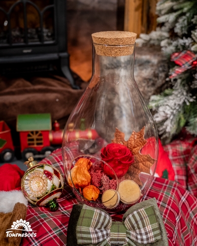Arrangement de roses éternelles sous cloche avec décoration de Noël.